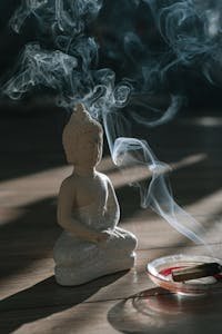 Burning Palo Santo Beside a Buddha Figurine